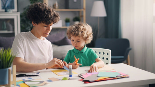 An adult and child sitting at a table using fine motor skills