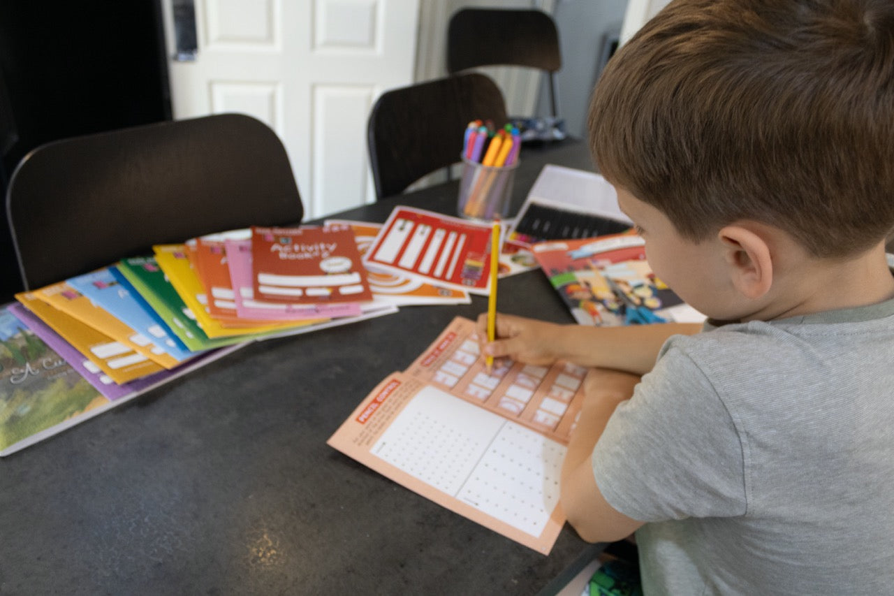 Child using a pencil to trace handwriting stroke patterns and practice controlled pencil movements in a handwriting workbook.