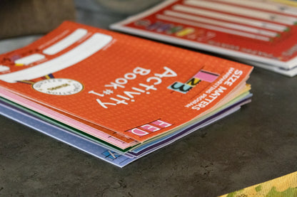 Close-up of a stack of colorful handwriting activity books designed to help children practice letter formation and handwriting skills.